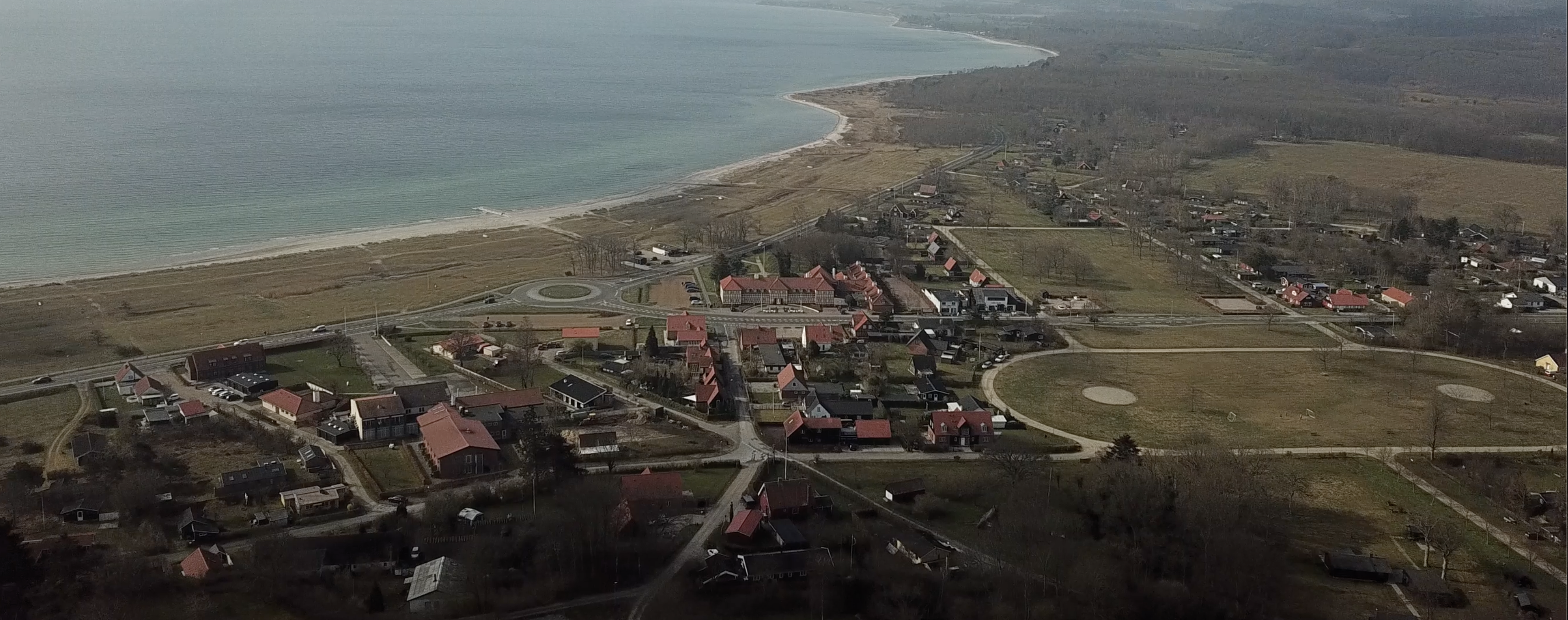 Luftfoto af kystnært sommerhusområde med strand og hav