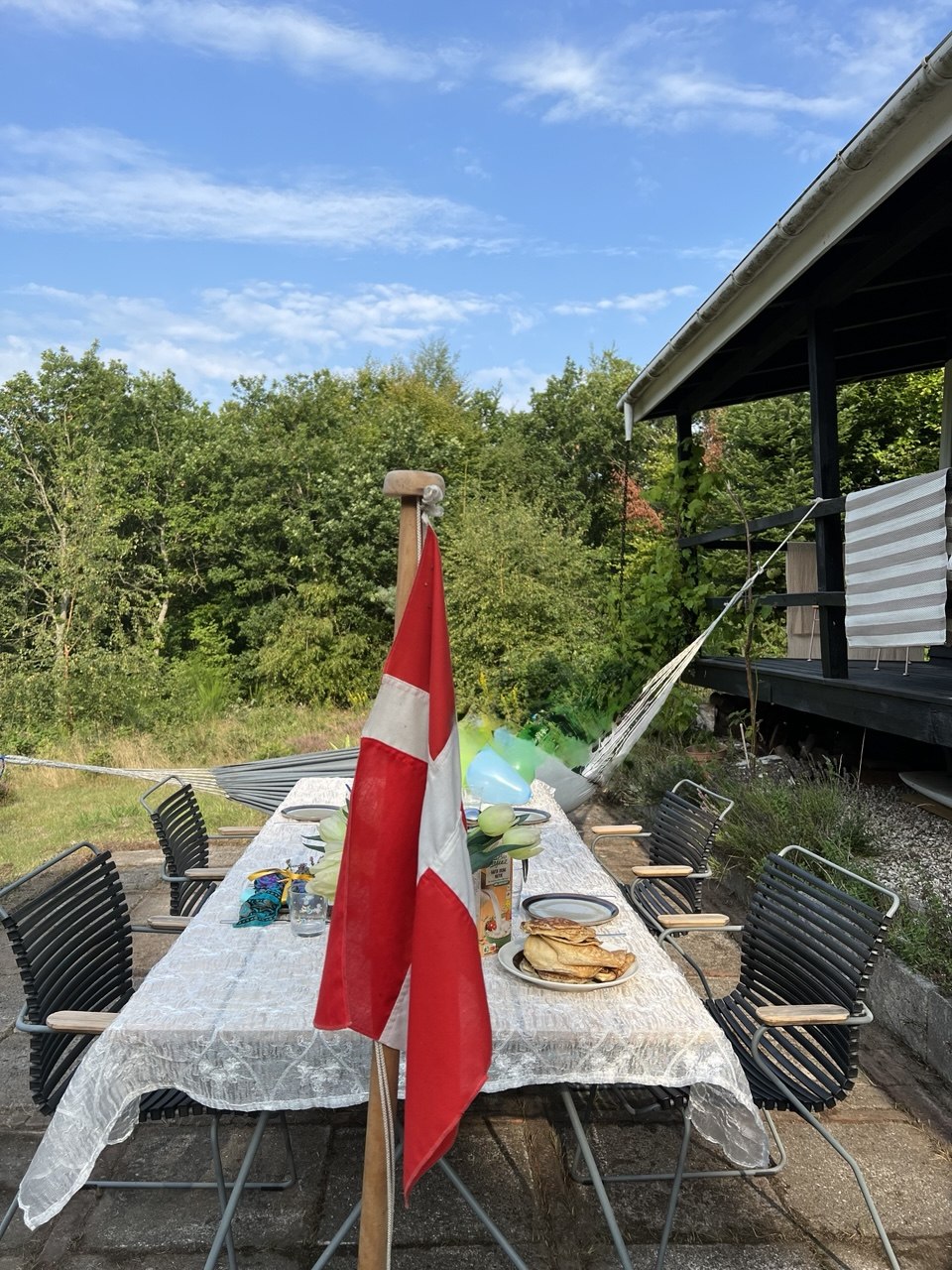 Terrasse med spisebord, stole og udsigt til haven
