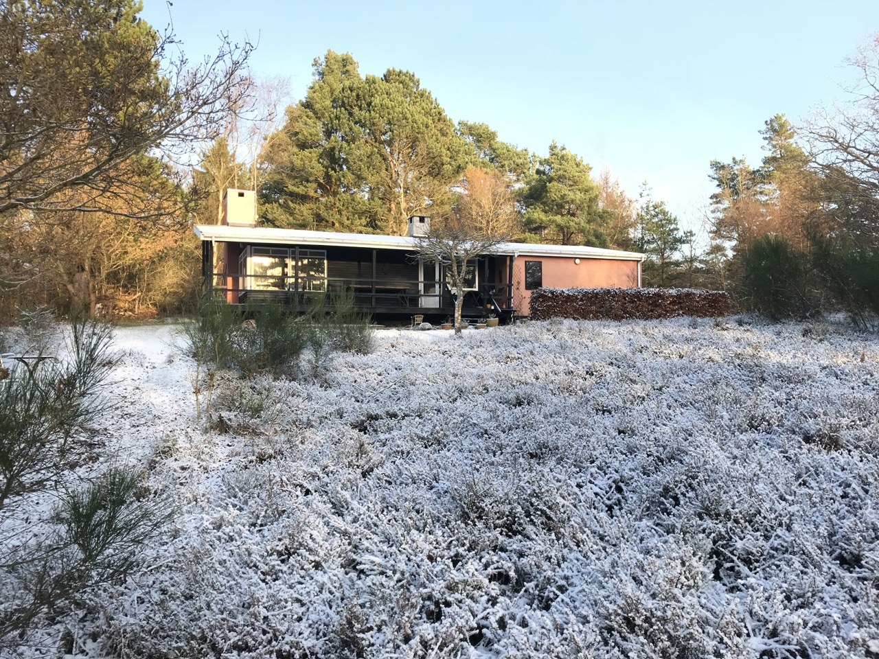 Sommerhusets terrasse i vinterlys med udsigt til haven